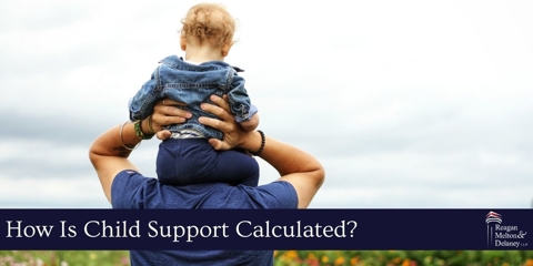 man carrying son on shoulders outside